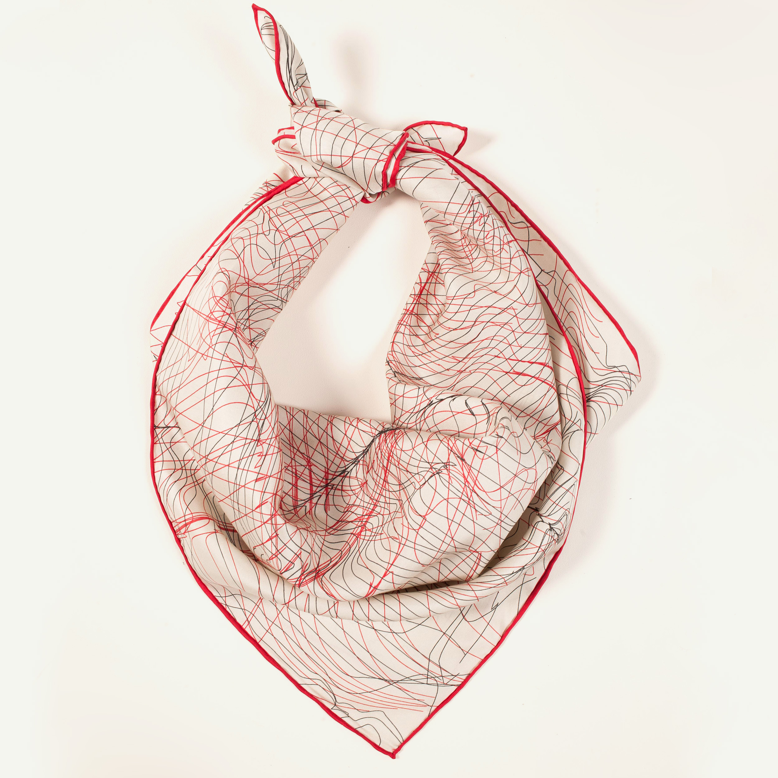 photo d'un carré en soie beige aux bordures rouges.